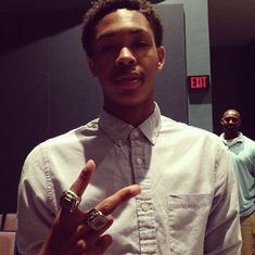 a man standing in front of a mirror making the peace sign with his fingers while wearing a button up shirt