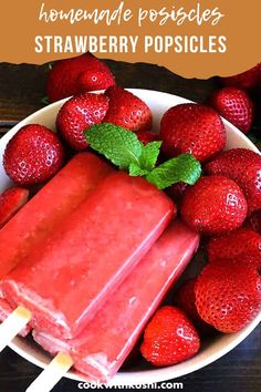 strawberry popsicles in a bowl with strawberries on the side