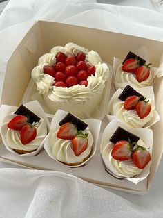 a box filled with cupcakes covered in white frosting and topped with strawberries