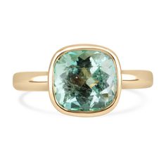 Displayed is a bespoke Colombian emerald solitaire cushion-cut ring, elegantly set in buttery 18K yellow gold. This exquisite piece features a 2.88-carat minty "chocolate chip" emerald, beautifully showcased in a bezel setting. Fully faceted, this gemstone gleams with exceptional shine, revealing its soft pastel green hue and charming carbon freckles, adding unique character to the stone. With excellent luster and an open bezel design, the emerald can be admired from every angle, making this ring a stunning choice for an engagement or a striking right-hand ring. Setting Style: Bezel  Setting Material: 18K Yellow Gold Setting Weight:  5.0 Grams Main Stone: Emerald Shape: Cushion Cut  Weight: 2.88-Carats Clarity: Transparent, Small Carbon Freckles  Color: Minty Light Green Luster: Excellent Cushion Cut Bezel Engagement Ring, Light Green Emerald, Emerald Solitaire Ring, Cushion Cut Solitaire, Emerald Set, Bezel Set Engagement Ring, Right Hand Ring, Cushion Cut Ring, Modern Engagement Rings