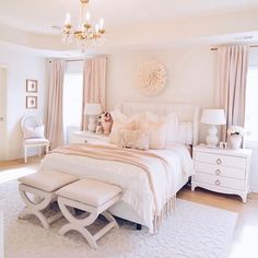 a white bedroom with a chandelier hanging from the ceiling and a large bed