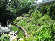 an outdoor patio with tables and chairs in the middle of a lush green hillside area