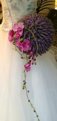 purple flowers and greenery are tied to the back of a wedding dress