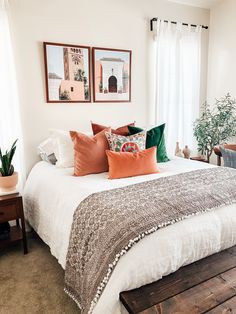 a bed with white sheets and pillows in a bedroom next to two pictures on the wall