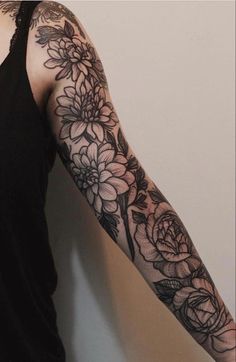 a woman wearing a black tank top with flowers on her arm and sleeve tattoo design