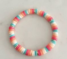 a bracelet with multicolored beads is displayed on a white surface, it looks like something out of space