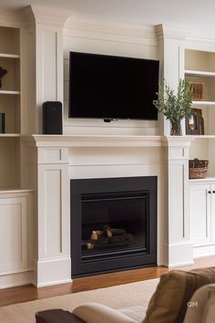 a living room with a fireplace and tv above the mantel, along with built - in bookcases