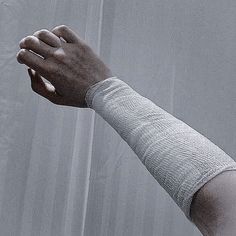 a bandaged arm and hand in front of a white curtain, with the wrist wrapped around it