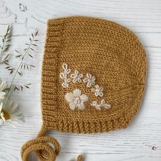 a crocheted hat with flowers on it and a string attached to the side