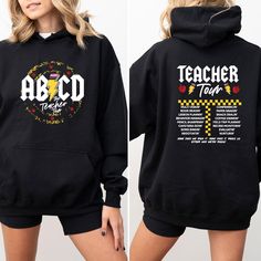 a woman wearing a black hoodie that says teacher tour