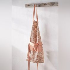 an apron hanging on a wall in front of a white wall with a wooden hanger