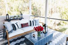 a white couch sitting on top of a tiled floor next to a table with flowers