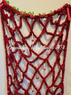 red crocheted wall hanging with green leaves and beaded beads on the edges