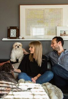 a man and woman sitting on a couch with their dog