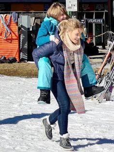 two women walking in the snow with skis behind them