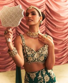 Capture attention in this emerald green embellished blouse with an attached dupatta, paired with a lehenga featuring cancan for dramatic flair. The intricate embellishments and elegant draping create a stunning ensemble, perfect for weddings and festive celebrations where you want to make a memorable entrance. Glamorous Lehenga With Unstitched Blouse, Green Lehenga With Cutdana And Kundan, Designer Green Lehenga With Unstitched Blouse, Green Kundan Sets For Reception, Glamorous Festive Green Sets, Elegant Green Lehenga With Mirror Work, Green Anarkali Set With Unstitched Blouse For Reception, Green Lehenga With Mirror Work And Kundan, Green Bollywood Lehenga With Unstitched Blouse