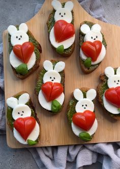 several small sandwiches with different toppings are arranged on a cutting board