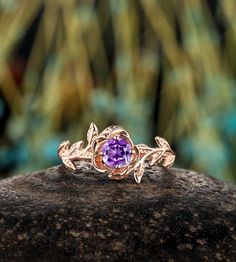 a ring with an amethorate stone in the center on top of a rock