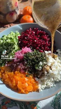 a bowl filled with different types of vegetables and gravy being drizzled over it