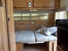 the inside of a camper with a bed and oven in it's corner