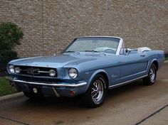 a blue mustang parked in front of a brick building