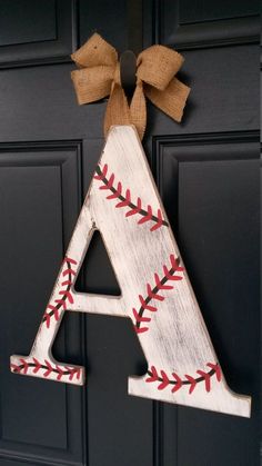 a baseball letter with a bow hanging on the front door, decorated with burlocks