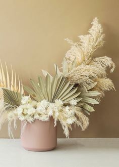 a pink vase filled with white flowers on top of a table next to a wall