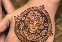 a woman's hand with henna tattoos on it and an image of the hindu god