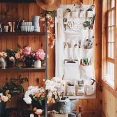 a room filled with lots of pots and flowers next to a wall covered in shelves