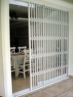 the sliding glass door is open to reveal an outside dining area with white chairs and table