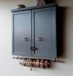 a blue cabinet with rings hanging from it's sides on a wall next to a clock