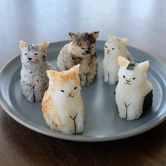 four small cat figurines sitting on a plate