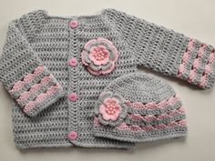 a crocheted sweater with pink flowers on the front and grey sleeves is shown