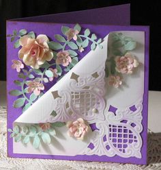 a close up of a greeting card with flowers and lace on the edge, in front of a white doily