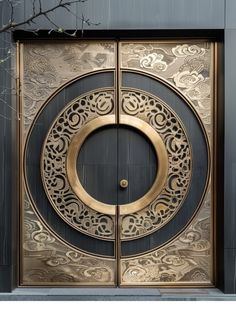 an ornate gold and black door with a circular design on the front, surrounded by branches