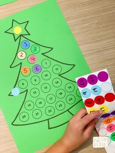 a child's hand holding up a christmas tree with numbers on it