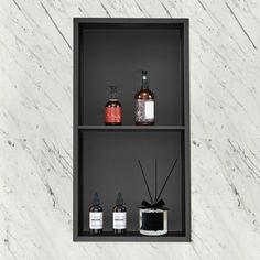 three shelves with different types of soaps and lotion bottles on them in front of a white marble wall