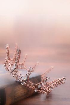 a tiara sitting on top of a book on a wooden table in front of a blurry background