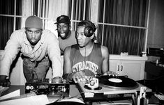 three young men sitting at a table in front of turntables and record players