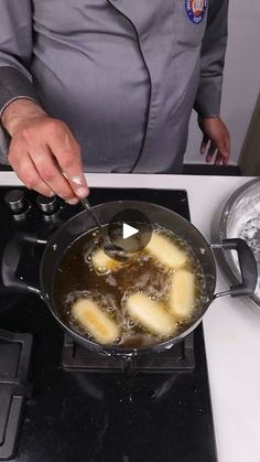 a woman cooking food on top of a stove next to a frying pan filled with liquid