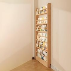 a bookshelf in the corner of a room with hard wood floors and white walls