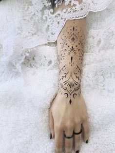 a woman's hand with a tattoo on it and an intricate design on the wrist