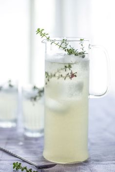 a pitcher filled with ice and herbs next to two glasses