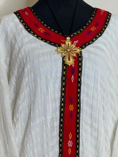 Ethiopian and Eritrean traditional top beautiful dress appears to be a traditional piece with intricate embroidery and a unique design. Could you provide Traditional Embroidered Dress With Woven Motifs, Folk Style Embroidered Dress With Woven Motifs For Festivities, Folk Embroidered Dress With Woven Motifs For Festive Occasions, Folk Style Embroidered Dress For Festive Season, Traditional Embroidered Dress With Traditional Patterns, Ceremonial Traditional Embroidered Dress, Traditional Long Sleeve Embroidered Dress, Traditional Embroidered Dress With Woven Motifs For Festival, Ceremonial White Traditional Wear With Woven Motifs