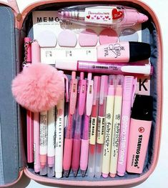 a pink suitcase filled with lots of different types of pens and pencils on top of each other