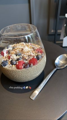 a bowl of oatmeal with berries and granola in it next to a spoon