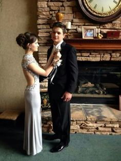 a man and woman standing next to each other in front of a stone fire place