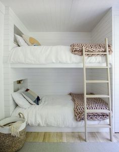 there are two bunk beds in this room with white walls and wood flooring on the bottom level