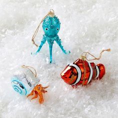 three christmas ornaments sitting on top of snow