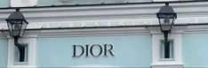 two black street lamps on the side of a blue building that says dior in large letters